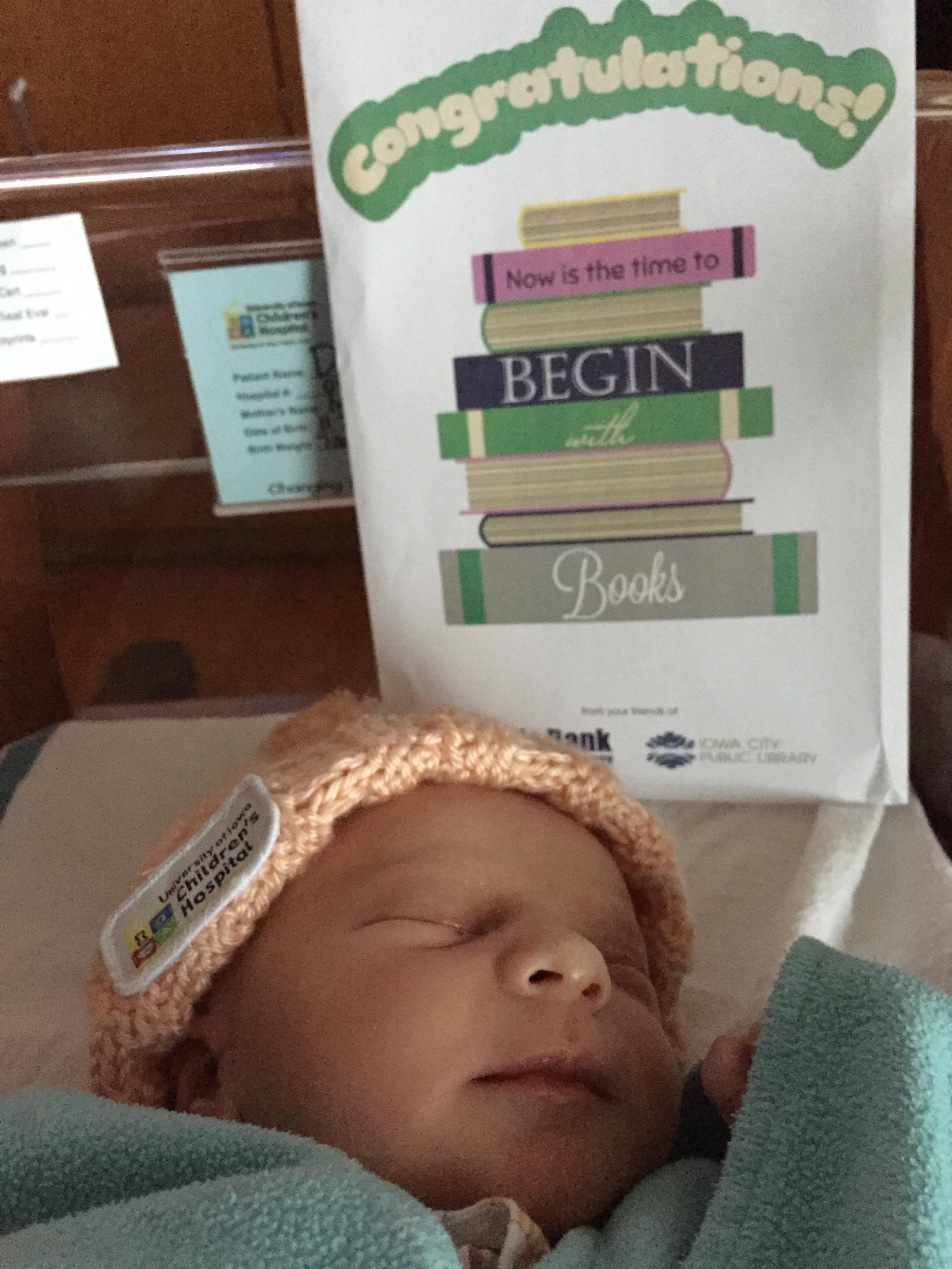 A newborn sleeps near a Begin with Books packet in 2015.