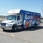 ICPL Bookmobile parked on a concrete lot, with blue sky visible.